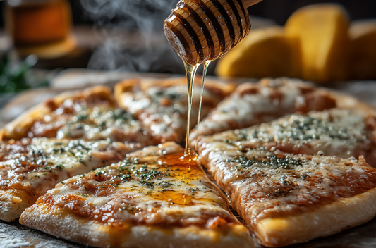 A pizza with honey being drizzled on top.